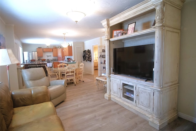 living room featuring baseboards, crown molding, and light wood finished floors