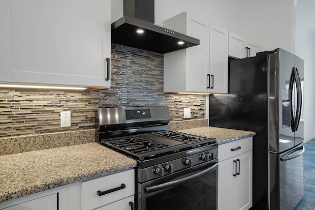 3 Cerro Cir, Lamy, NM 87540 - kitchen with decorative backsplash, white cabinets, stainless steel gas range oven, black fridge, and wall chimney range hood