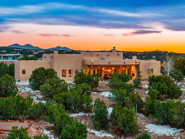 back of property featuring stucco siding, a mountain view, and a chimney