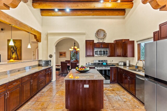 kitchen featuring a center island, stainless steel appliances, a sink, arched walkways, and beamed ceiling