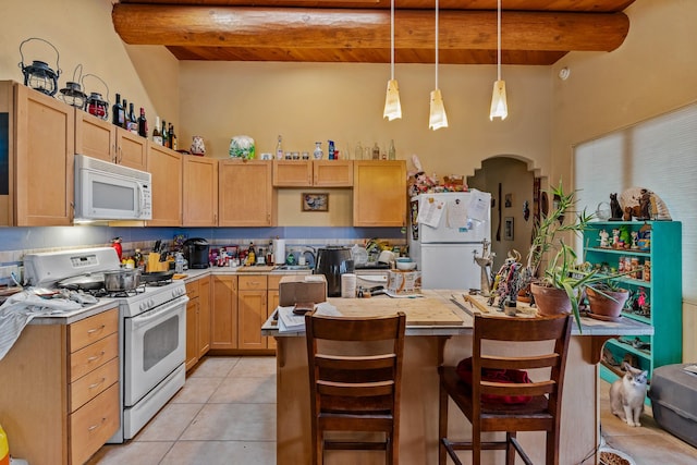 kitchen with arched walkways, light countertops, beamed ceiling, and white appliances