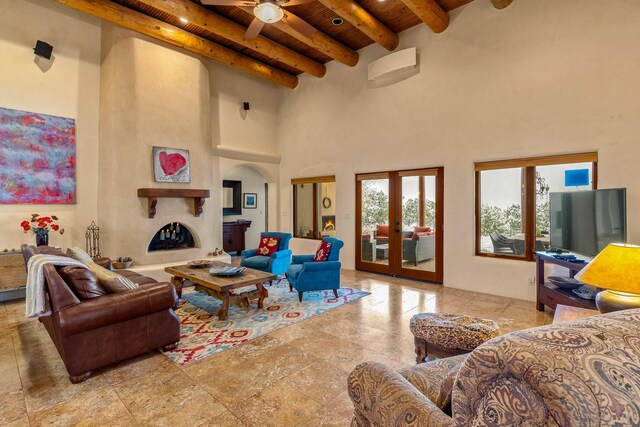 living room with a fireplace, a ceiling fan, beam ceiling, french doors, and wood ceiling
