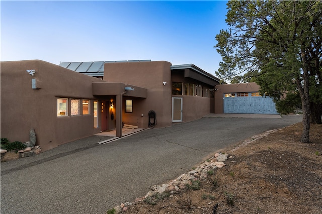 6 Overlook Rd, Santa Fe, NM 87505 - pueblo-style home with metal roof, aphalt driveway, a garage, a standing seam roof, and stucco siding