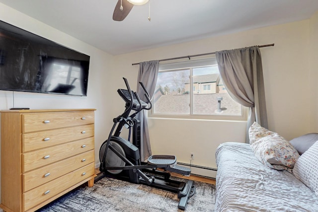 exercise room with ceiling fan, wood finished floors, and a baseboard heating unit
