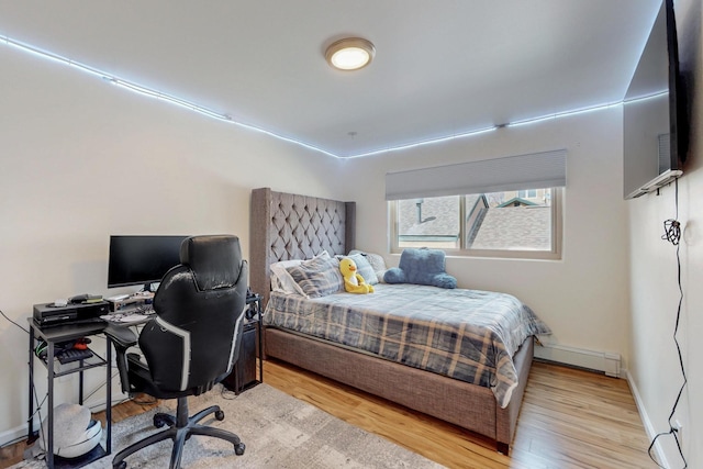 bedroom featuring baseboards, light wood-style floors, and baseboard heating