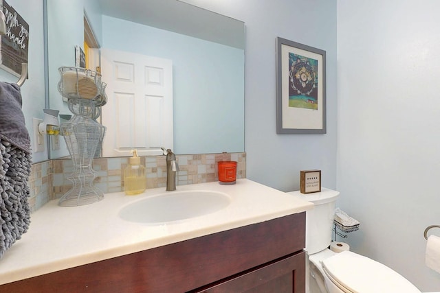 half bathroom featuring toilet, backsplash, and vanity