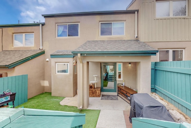 rear view of house featuring a fenced backyard, stucco siding, and a shingled roof
