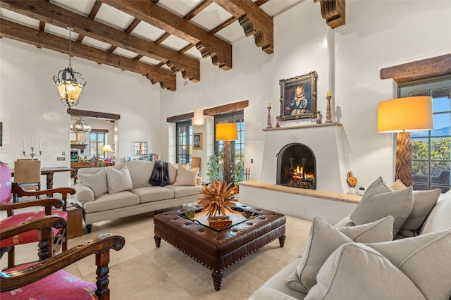 living area featuring an inviting chandelier, beam ceiling, a fireplace, tile patterned floors, and a towering ceiling