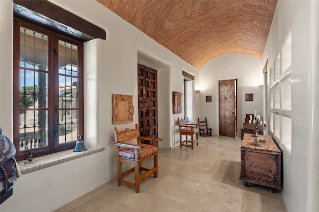 corridor featuring french doors, lofted ceiling, and brick ceiling