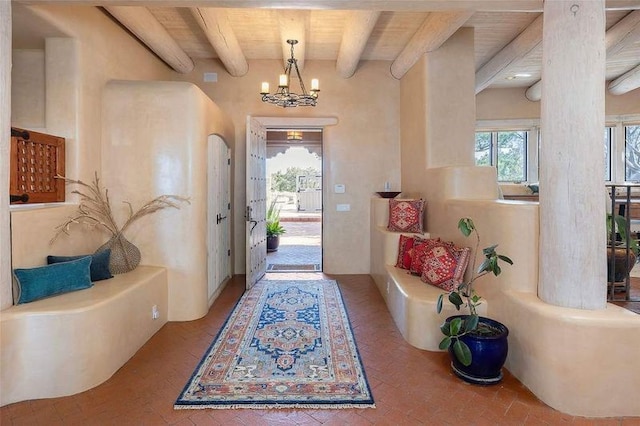 24 Paintbrush Cir, Santa Fe, NM 87506 - entrance foyer with brick flooring, beam ceiling, a chandelier, and ornate columns