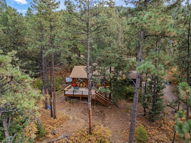 exterior space with a view of trees, a wooden deck, and stairs
