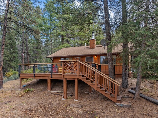back of house with a wooden deck, a shingled roof, stairway, and a chimney