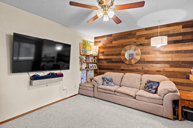 living room with baseboards, ceiling fan, carpet, a textured ceiling, and wooden walls