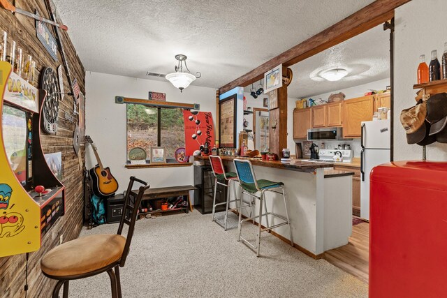 kitchen featuring freestanding refrigerator, a textured ceiling, a peninsula, visible vents, and stainless steel microwave