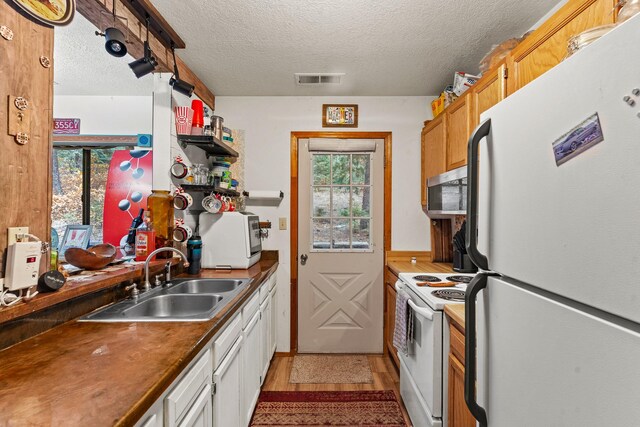 kitchen with a sink, white appliances, white cabinets, and a wealth of natural light
