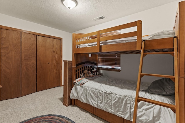 bedroom featuring a textured ceiling, a closet, visible vents, a wainscoted wall, and carpet floors