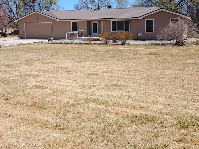single story home with a front yard, an attached garage, metal roof, and driveway