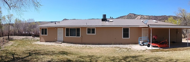 rear view of house featuring a mountain view, metal roof, and a lawn