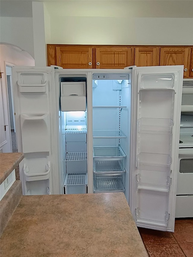 room details with white electric range, brown cabinets, light countertops, and refrigerator