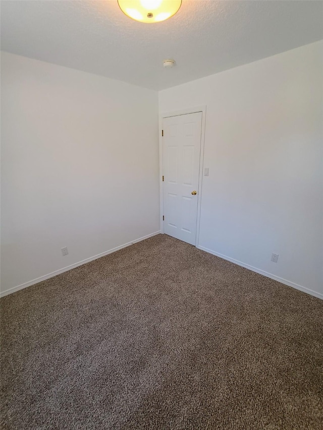 carpeted empty room featuring baseboards and a textured ceiling