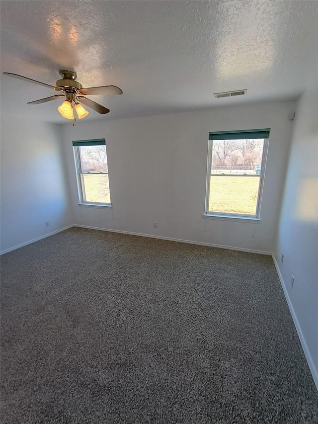 empty room featuring a textured ceiling, a ceiling fan, visible vents, and carpet floors