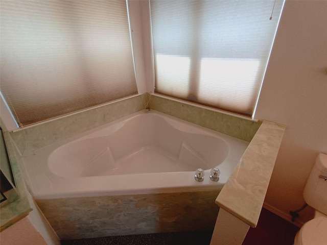 bathroom with a garden tub and toilet