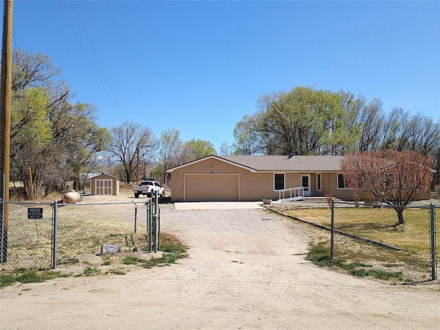 view of front of house featuring an attached garage, a storage shed, driveway, and fence
