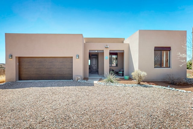 adobe home with driveway, a garage, and stucco siding