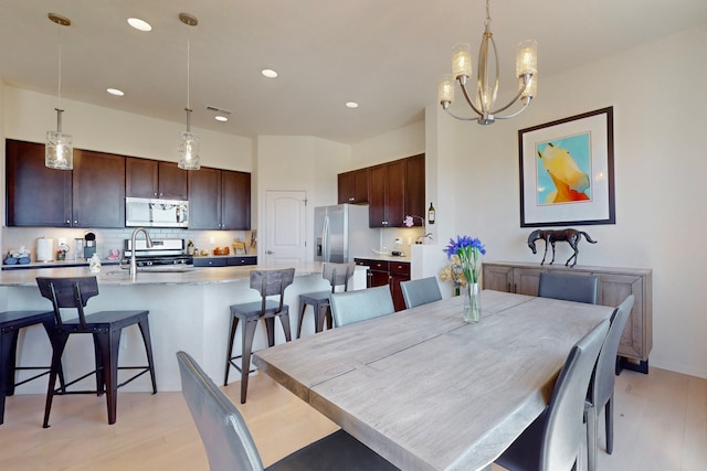 dining space with recessed lighting, light wood-style floors, and an inviting chandelier