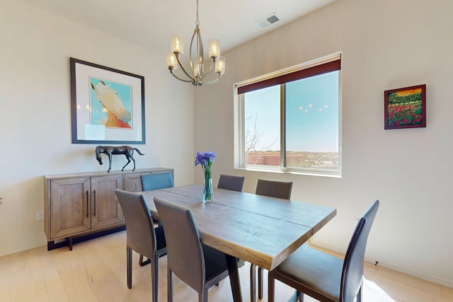dining room featuring a chandelier, light wood finished floors, baseboards, and visible vents