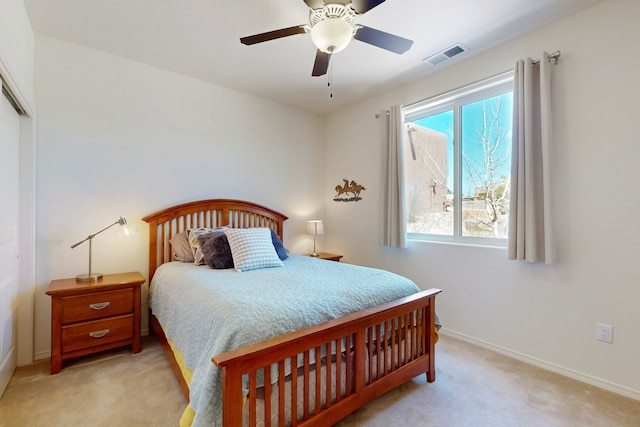 bedroom with visible vents, baseboards, a closet, a ceiling fan, and light carpet