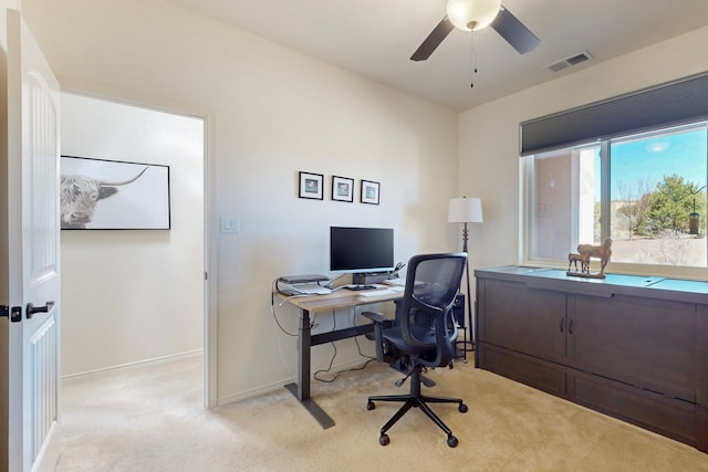 office featuring visible vents, baseboards, ceiling fan, and light colored carpet