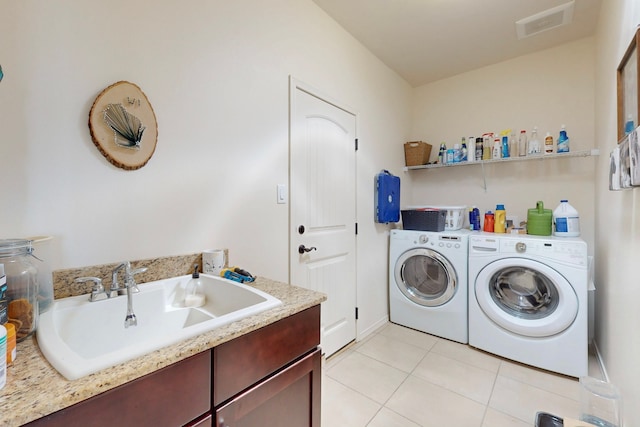 washroom featuring a sink, visible vents, washing machine and clothes dryer, and light tile patterned floors