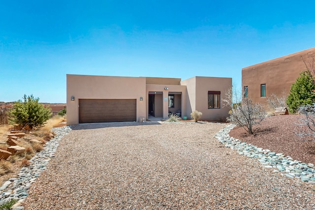 adobe home with a garage, driveway, and stucco siding