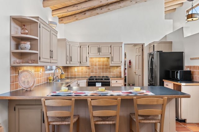 kitchen featuring tasteful backsplash, a peninsula, black appliances, beam ceiling, and a sink