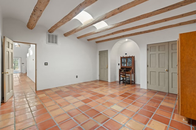 unfurnished room with arched walkways, light tile patterned floors, beam ceiling, and visible vents