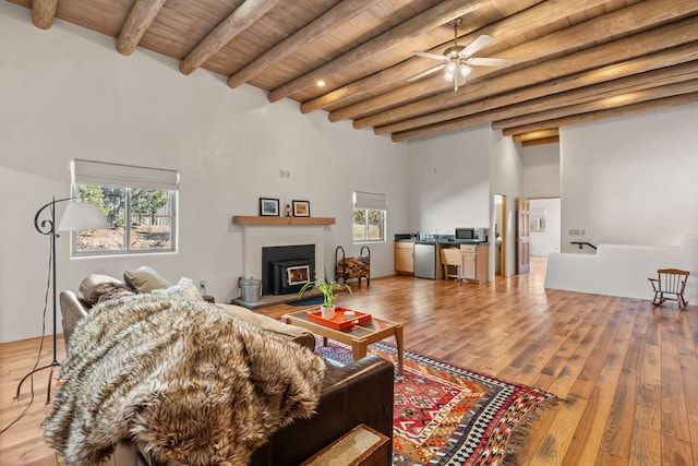 living area with a warm lit fireplace, beam ceiling, wooden ceiling, and hardwood / wood-style floors