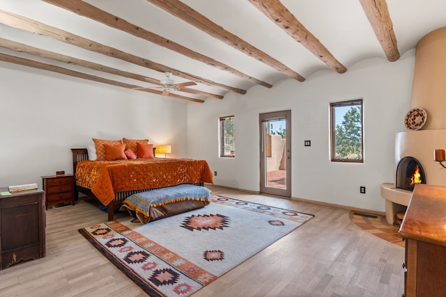 bedroom with light wood-style flooring, beam ceiling, and access to exterior