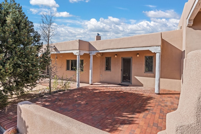 view of front facade with a chimney, a patio area, and stucco siding