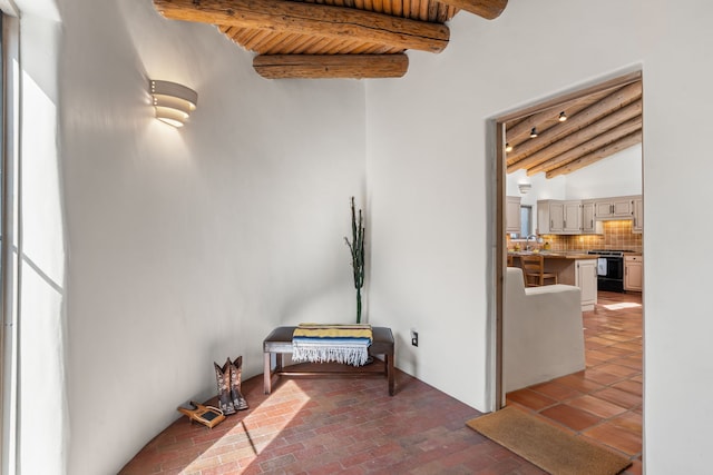 corridor with a sink, beam ceiling, and brick floor