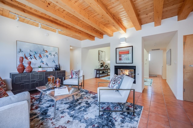 living area with tile patterned floors, wood ceiling, a multi sided fireplace, and beam ceiling