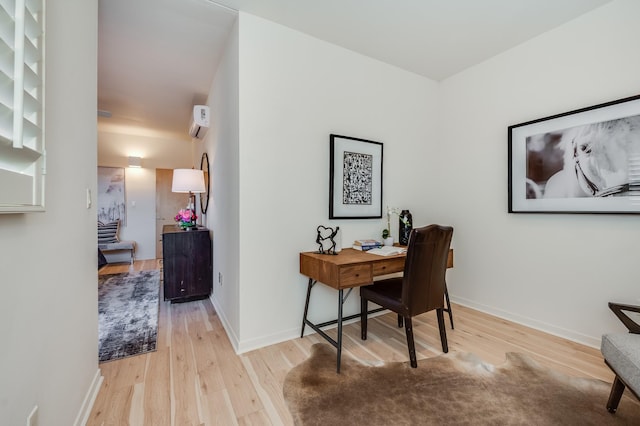 office space with light wood-style flooring, a wall mounted air conditioner, and baseboards