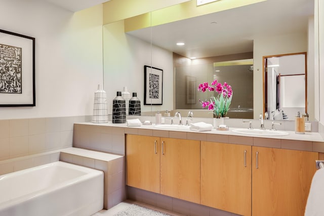 bathroom with double vanity, a garden tub, a sink, and a stall shower