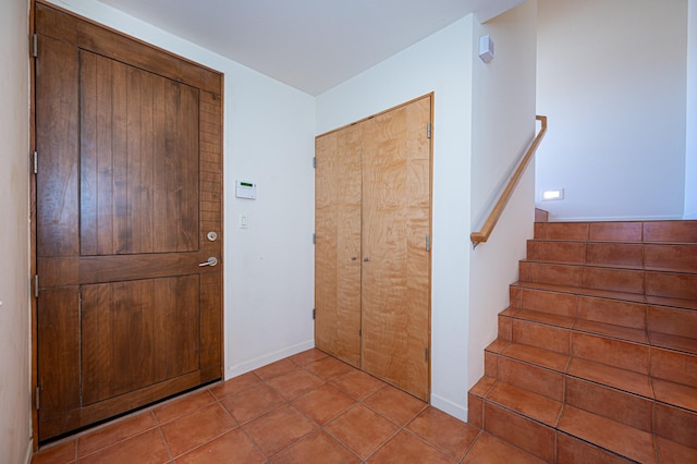 foyer featuring tile patterned floors, baseboards, and stairs