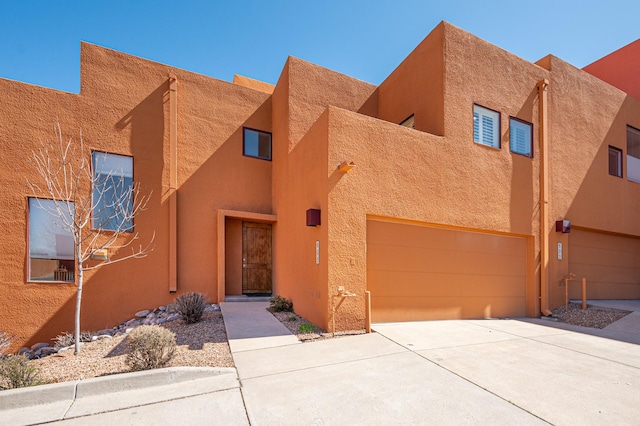 adobe home featuring stucco siding, a garage, and concrete driveway