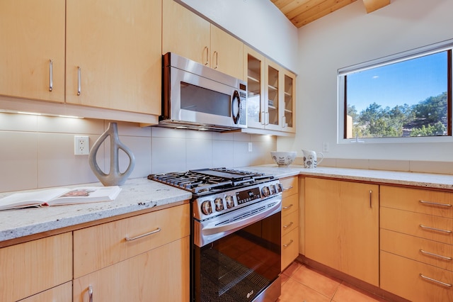 kitchen with appliances with stainless steel finishes, light brown cabinetry, and light stone countertops