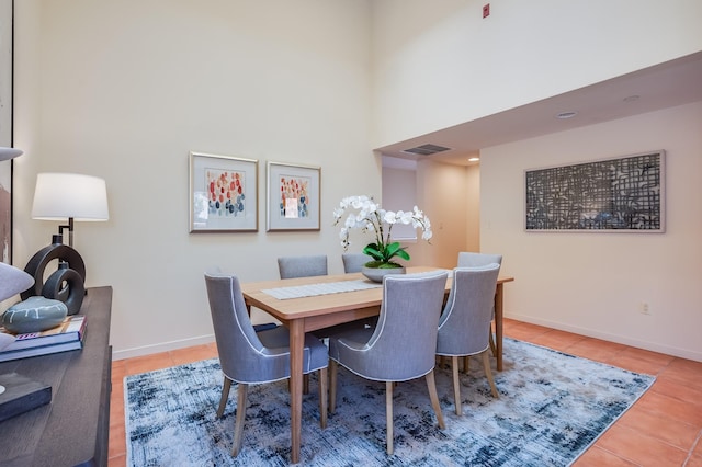 tiled dining space featuring a towering ceiling, baseboards, and visible vents