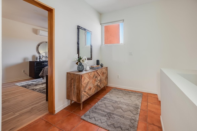 corridor featuring tile patterned floors, a wall unit AC, and baseboards