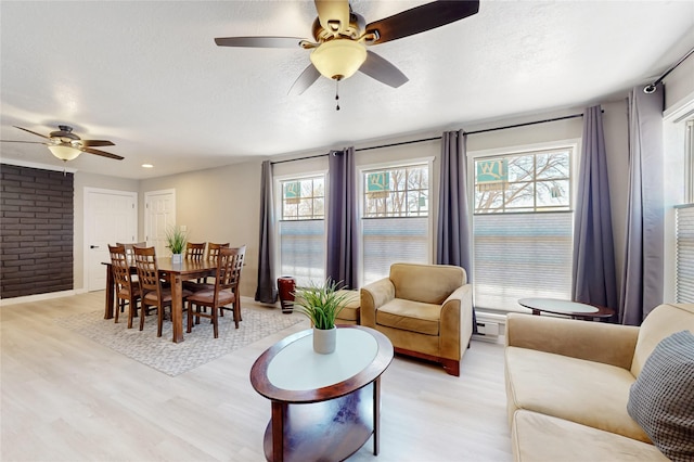 living room featuring light wood-style flooring, a textured ceiling, and ceiling fan