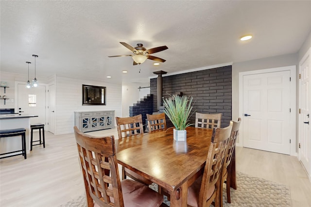 dining area featuring recessed lighting, a wood stove, light wood finished floors, and a ceiling fan